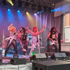 Rokkula en el escenario, vestidos de banda de rock de los 80.